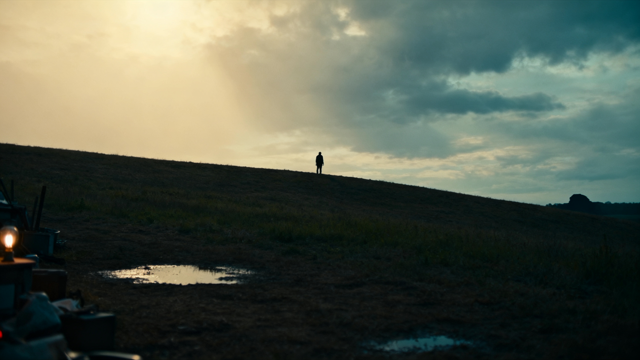 Silueta solitaria sobre colina al atardecer, paisaje oscuro con atmósfera de misterio y suspense